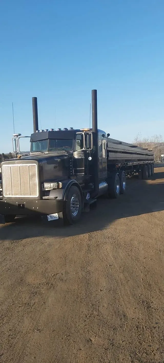 Peterbilt et plateau chargés de bois de sciage sur un chemin de terre