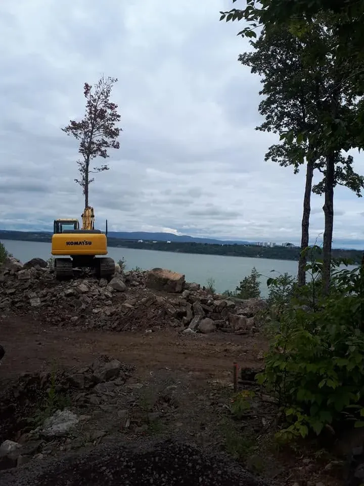 Pelle Komatsu au bord d’un plan d’eau, sur un terrain de roche fraîchement dégagé