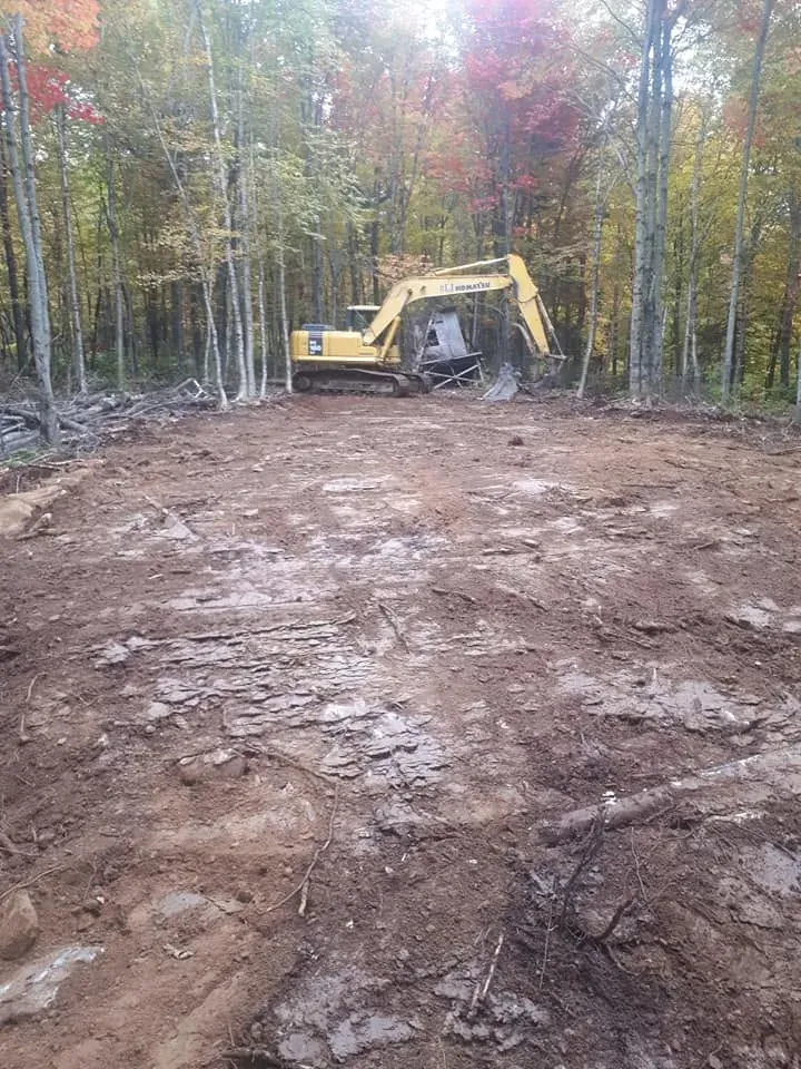 Terrain déboisé en automne, pelle Komatsu au fond entre les arbres