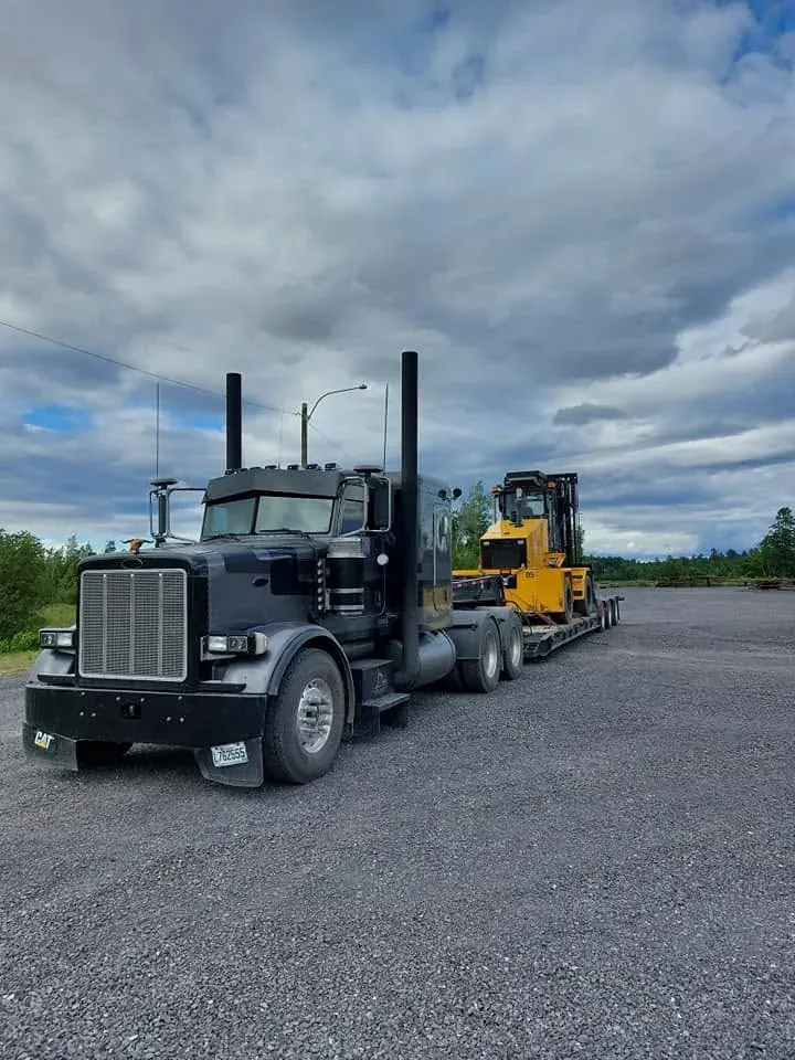 Peterbilt et fardier chargés d’un chariot élévateur de chantier